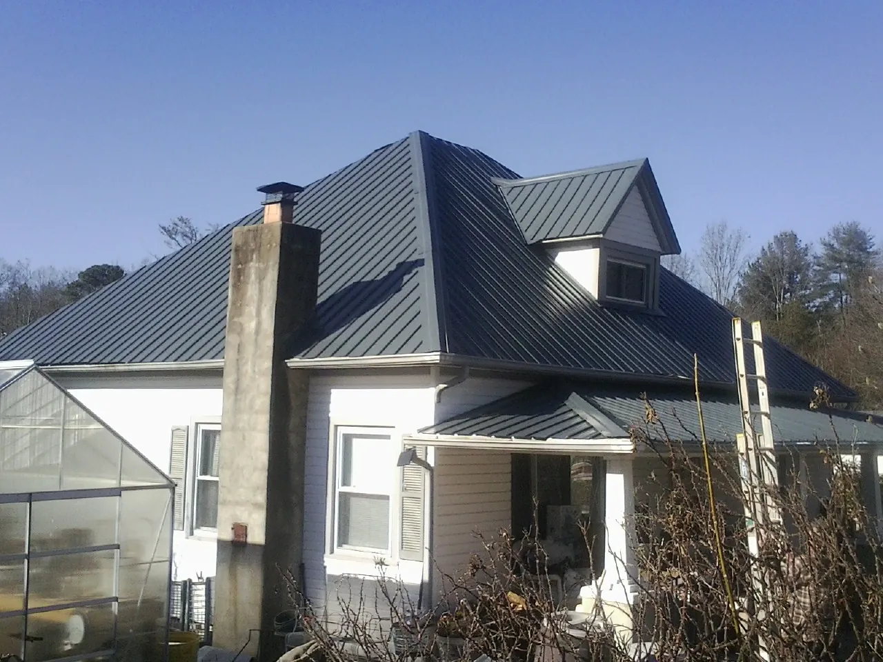 Dark blue standing seam metal roof on a white farmhouse with dormer — Slate & Tile Roof Repair by Roofing Brothers in Klingerstown