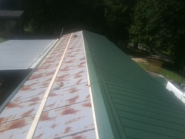 Old rusted panels beside newly installed green metal roofing — Wind Damage Roof Repair by Roofing Brothers in Klingerstown