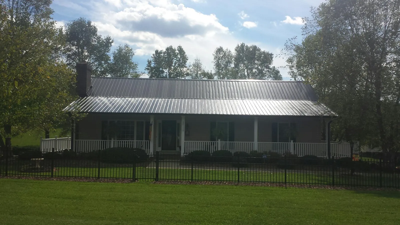 Gray metal roof on a brick ranch with a full width front porch — Gutter Guard Installation work by our crew in Klingerstown