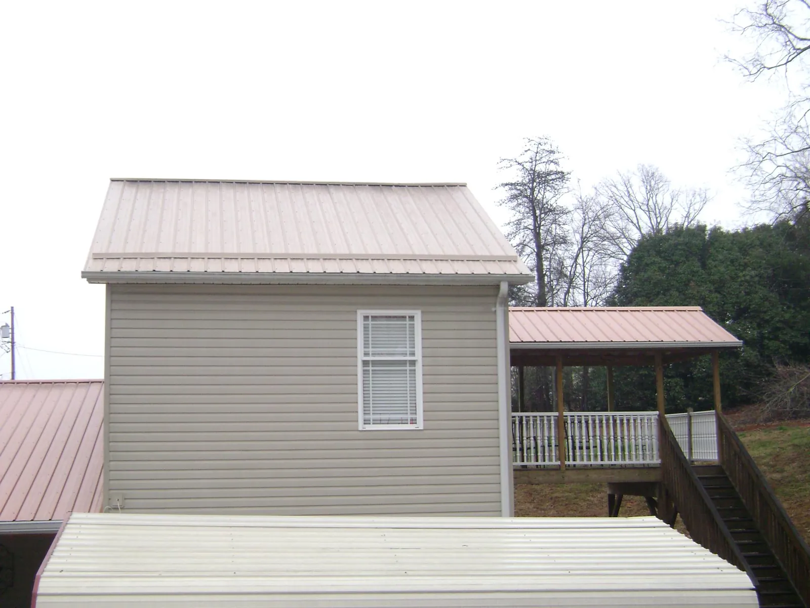 Tan metal roofs on a two story addition and attached porch, from a Roof Replacement job in Klingerstown
