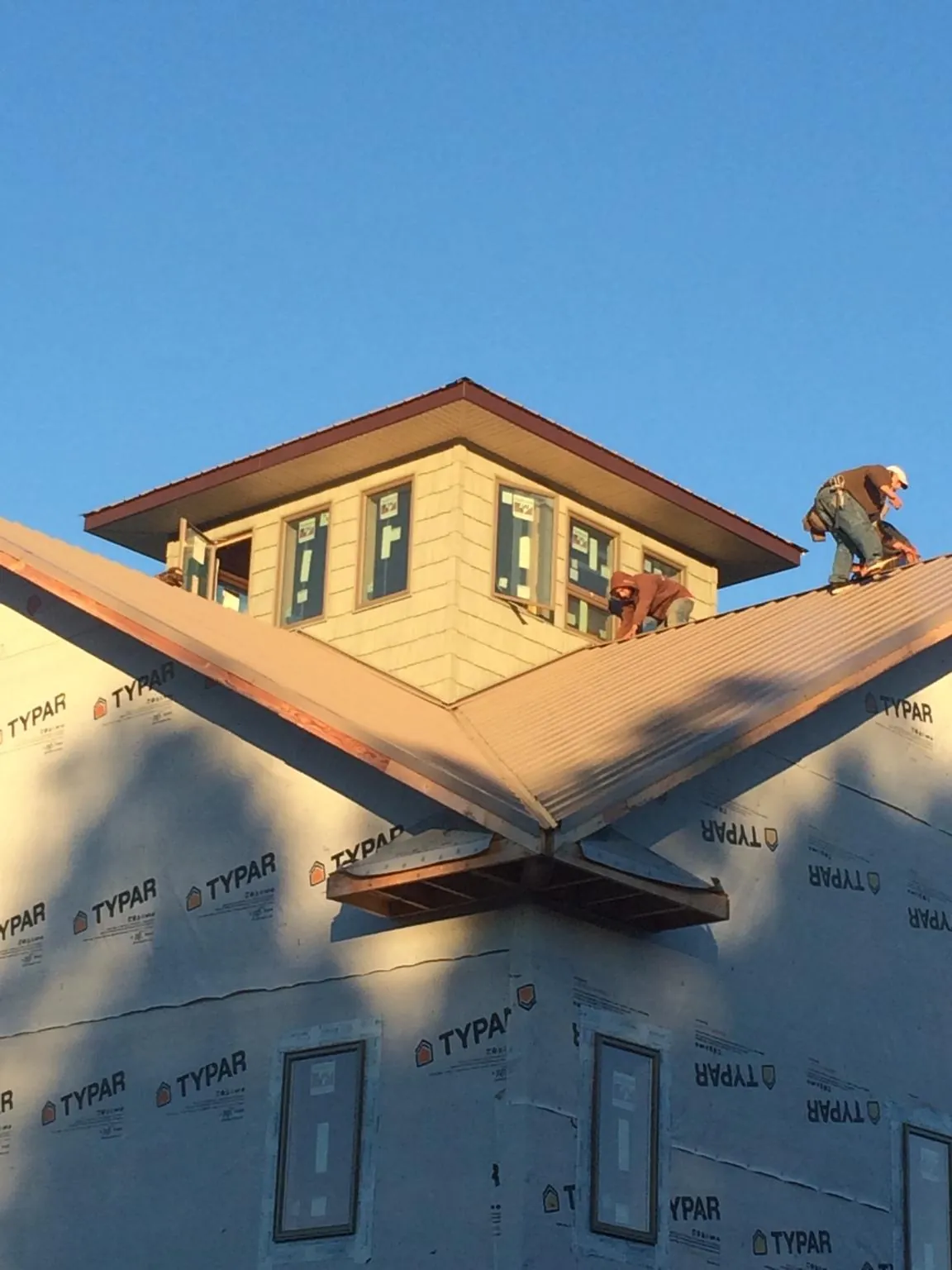 Roofers working around a rooftop cupola on a new metal roof at sunset — Roof Waterproofing in Klingerstown by Roofing Brothers